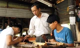 Ông Nguyễn Văn Tiếp hướng dẫn chạm khắc cho thanh niên mới học nghề. Ảnh: Thanh Trần