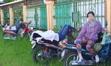 Hai phụ huynh ngủ trên xe gắn máy để chờ con.