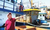 Thuyền trưởng Lê Văn Thãi từng tham gia tổ đội đi giữ biển. Bên cạnh anh là con tàu mục nát của ông Nguyễn Văn Lý. Ảnh: PV.