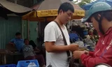 Một “người lạ” đứng thu tiền xe vào chợ.