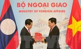 Phó Thủ tướng, Bộ trưởng Ngoại giao Phạm Bình Minh và Bộ trưởng Ngoại giao Lào Saleumxay Kommasith trao đổi tượng trưng hai ấn phẩm văn kiên pháp lý biên giới Việt Nam-Lào. (Ảnh: Nguyễn Khang/TTXVN)