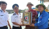 Bí thư T.Ư Đoàn Nguyễn Phi Long và Đại tá Nguyễn Nghiêm Long, Phó Chính ủy Vùng Cảnh sát biển 3 trao tặng hộp thuốc cho ngư dân xã Phước Thuận, chiều 28/3. Ảnh: Nguyễn Minh.