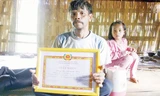 Ông Bnươch Bốn (62 tuổi) với tấm giấy khen được Đảng bộ xã A Rooi trao tặng vì hành động tình nguyện hiến đất làm đường. Ảnh: Thanh Trần.