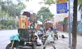 Công nhân môi trường và xe rác cao quá đầu người trên phố Hà Nội. Nếu không chất thêm rác lên, họ sẽ không kịp giờ thu dọn rác. Ảnh: Trường Phong