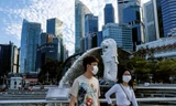 Hai thanh niên đeo khẩu trang đi ngang tượng ngư sư ở Singapore. Ảnh: AP.