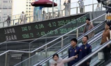 Bảng điện tử hiển thị chỉ số chứng khoán Thượng Hải và Thâm Quyến khi mọi người đi trên cầu ở khu tài chính Lục Gia Chủy ở Thượng Hải ngày 3/4. (Ảnh: Reuters)