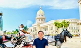 Tác giả trên nền một chiếc xe cổ đi ngang qua toà nhà Capitolio nổi tiếng ở La Habana Ảnh: Minh Vũ