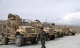 Một binh sĩ quân đội Afghanistan đi ngang qua các phương tiện chống mìn MRAP, bị bỏ lại sau khi quân đội Mỹ rời căn cứ không quân Bagram, ở tỉnh Parwan, phía bắc Kabul, Afghanistan, ngày 5 tháng 7 năm 2021. Quân Mỹ rời Sân bay Bagram của Afghanistan sau gần gần 20 năm đồn trú.
