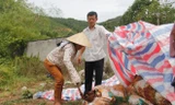 Người dân chọc thủng một bao tải chứa chất thải để kiểm tra bên trong. Ảnh: Thanh Trần. 