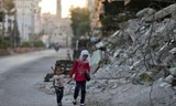 Hai trẻ em đi bộ qua một tòa nhà đổ nát trong ngày lễ Eid al-Fitr tại khu phố Douma, Damascus, Syria. Ảnh: Reuters.