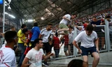 Khán giả sợ hãi bỏ chạy khi những cổ động viên quá khích của hai đội lao vào nhau. 