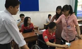 Thí sinh Đỗ Thị Lan Anh, bị tai nạn gãy chân trái, nẹp sưng to nên phải ngồi xe lăn vào phòng thi.