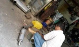 Một thợ đang cắt, độ lại pô mô tô tại tiệm ông H.