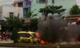 Chiếc xe taxi sau khi bị ép văng qua bên kia đường rồi bốc cháy ngùn ngụt. Ảnh facebook một bạn đọc.