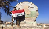 Một binh sĩ Iraq giương cờ trên trụ sở hành chính ở Ramadi, Iraq, ngày 28/12.