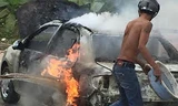Một người dùng chậu nước hắt vào chiếc xe cháy nhưng ngọn lửa vẫn bùng lên dữ dội, bao trùm cả xe.