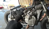 Thợ độ xe đang độ thay thế pô ống xả bằng hợp kim cho một chiếc xe độ phân khối lớn.