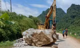 Lực lượng chức năng huy động máy móc giải tỏa tảng đá .Ảnh: V. Thương