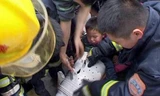 Các nhân viên cứu hộ đang giải cứu bé Tao Peng ra khỏi lồng máy giặt.
