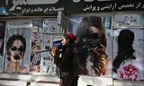 Một lính Taliban đi tuần ở Kabul. Đằng sau, các hình ảnh quảng cáo phụ nữ đã bị xóa bỏ