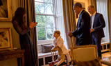 Hoàng tử bé George chơi ngựa gỗ cùng với Công nương Catherine, đứng cạnh là Tổng thống Mỹ Barack Obama (thứ 2 từ phải sang) và Hoàng tử William, tại Cung điện Kensington ngày 22/4. Ảnh: PA/Reuters.