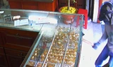 Tên cướp dùng búa đẽo đập vỡ tủ kính hốt đi nhiều nữ trang. Ảnh: Trích từ camera tiệm vàng 