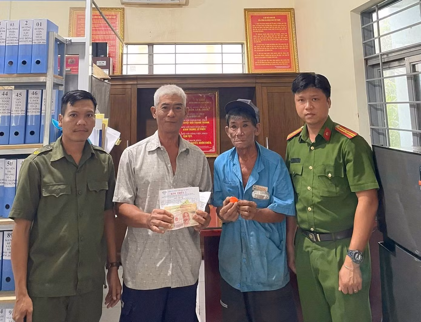 Ông Cà (áo trắng) trả lại tài sản cho ông Thành (áo xanh) tại Công an xã Phước An Ông Cà (áo trắng) trả lại tài sản cho ông Thành (áo xanh) tại Công an xã Phước An