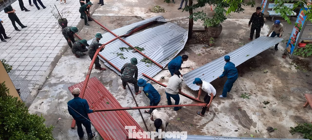 Lực lượng bộ đội, dân quân tự vệ, người dân giúp nhà trường dọn dẹp phần mái bị lốc cuốn bay. Lực lượng bộ đội, dân quân tự vệ, người dân giúp nhà trường dọn dẹp phần mái bị lốc cuốn bay.