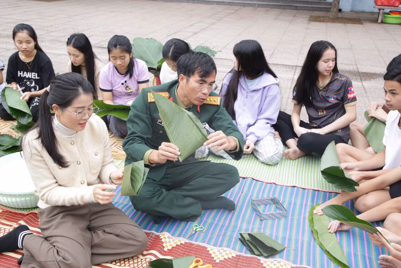 Các cán bộ chiến sĩ hướng dẫn từ việc chọn lá, cắt lá, chuẩn bị nguyên vật liệu đến việc gấp lá và gói bánh.