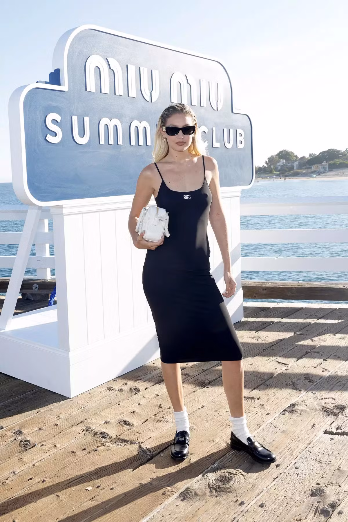 Gigi Hadid diện một chiếc đầm ôm sát tối màu và đi tất với giày da loafer tại show của MiuMiu. Gigi Hadid diện một chiếc đầm ôm sát tối màu và đi tất với giày da loafer tại show của MiuMiu.
