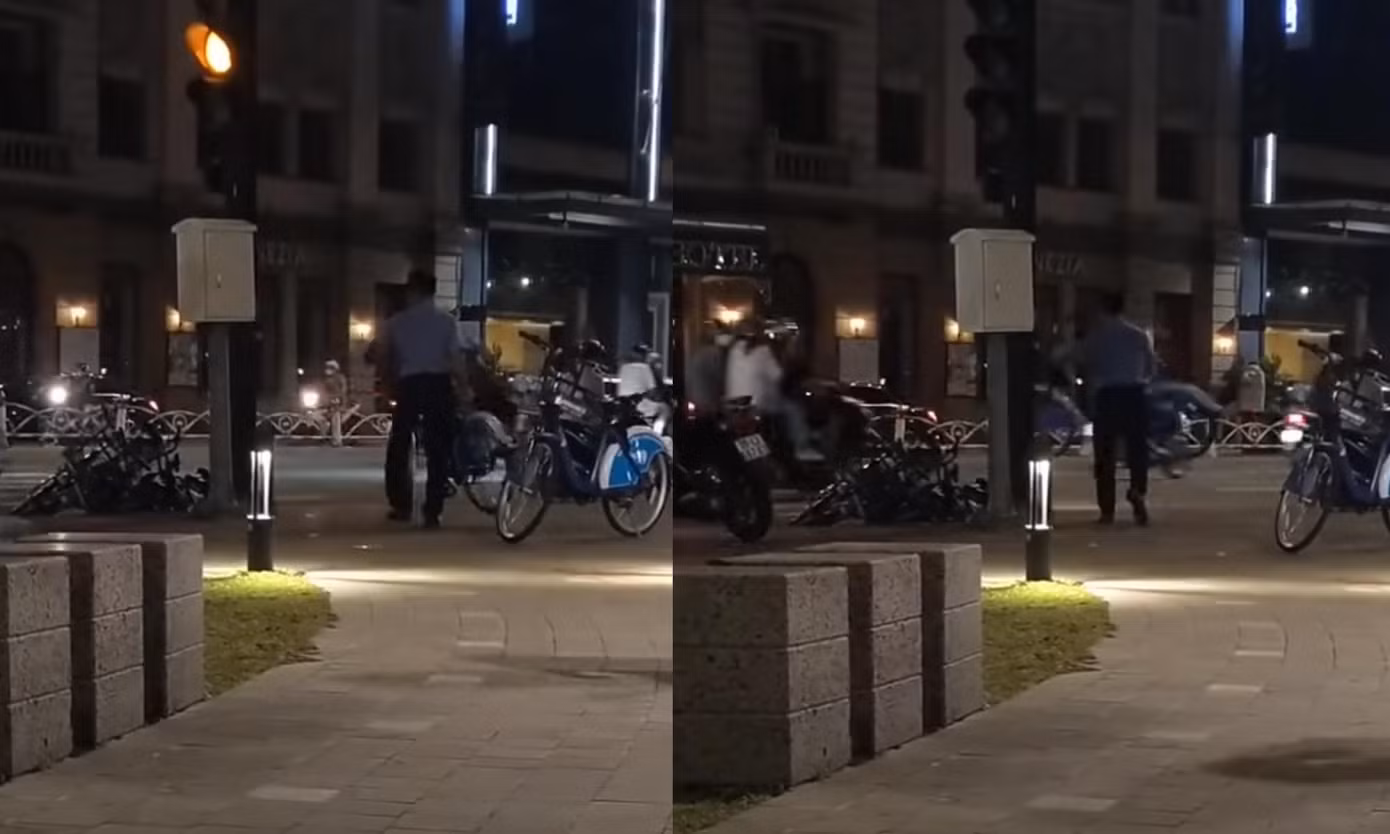Nam bảo vệ quăng xe đạp công cộng từ vỉa hè xuống lòng đường ở khu vực công viên Bến Bạch Đằng, quận 1. (Ảnh chụp từ clip)