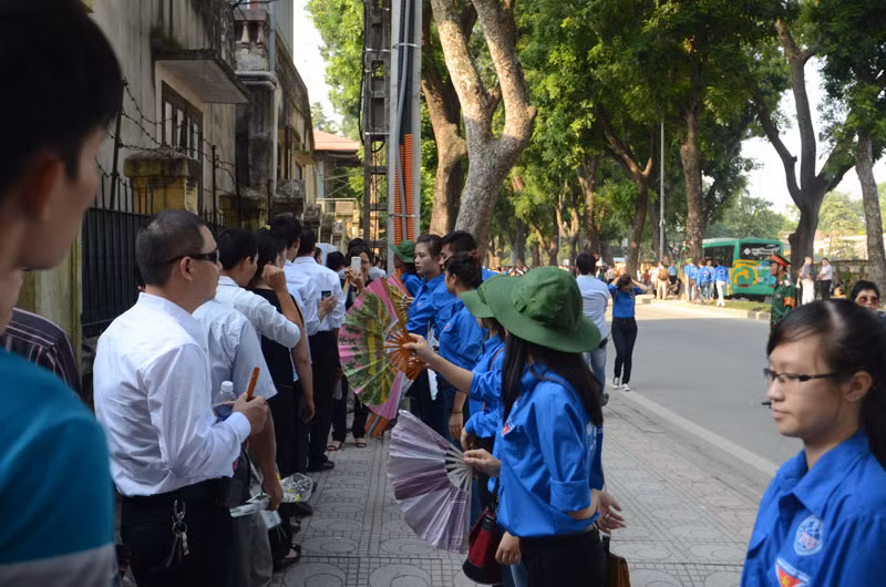 Những sinh viên tình nguyện quạt cho người dân đang xếp hàng