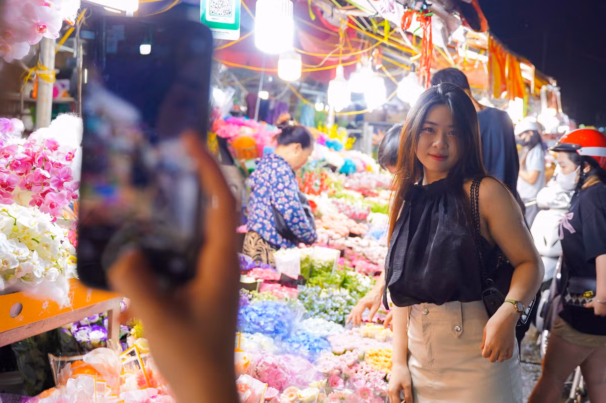 Nhiều bạn trẻ tranh thủ ghi lại những bức ảnh kỷ niệm giữa rừng hoa rực rỡ muôn màu sắc. "Mình rất thích khung cảnh chợ hoa đêm Quảng Bá những ngày này, nhộn nhịp nhưng không kém phần lãng mạn", bạn nữ chia sẻ.