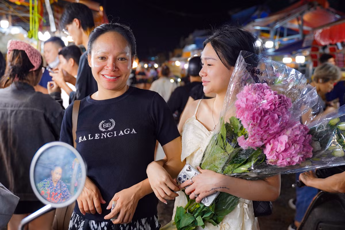 Hai mẹ con dẫn nhau đi tận hưởng không khí chợ đêm, chọn lựa một bó hoa tươi thắm nhất để mang về.