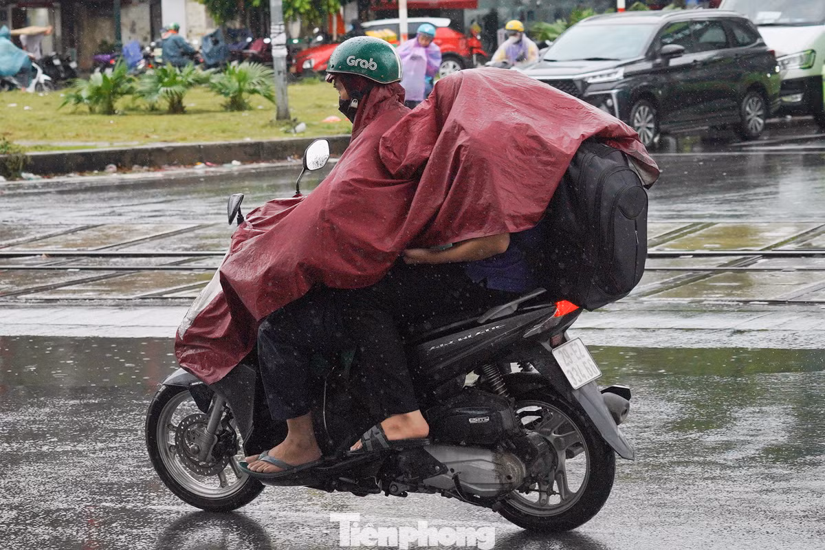 Trời mưa khiến việc ra bến xe trở nên khó khăn trong lớp áo mưa.