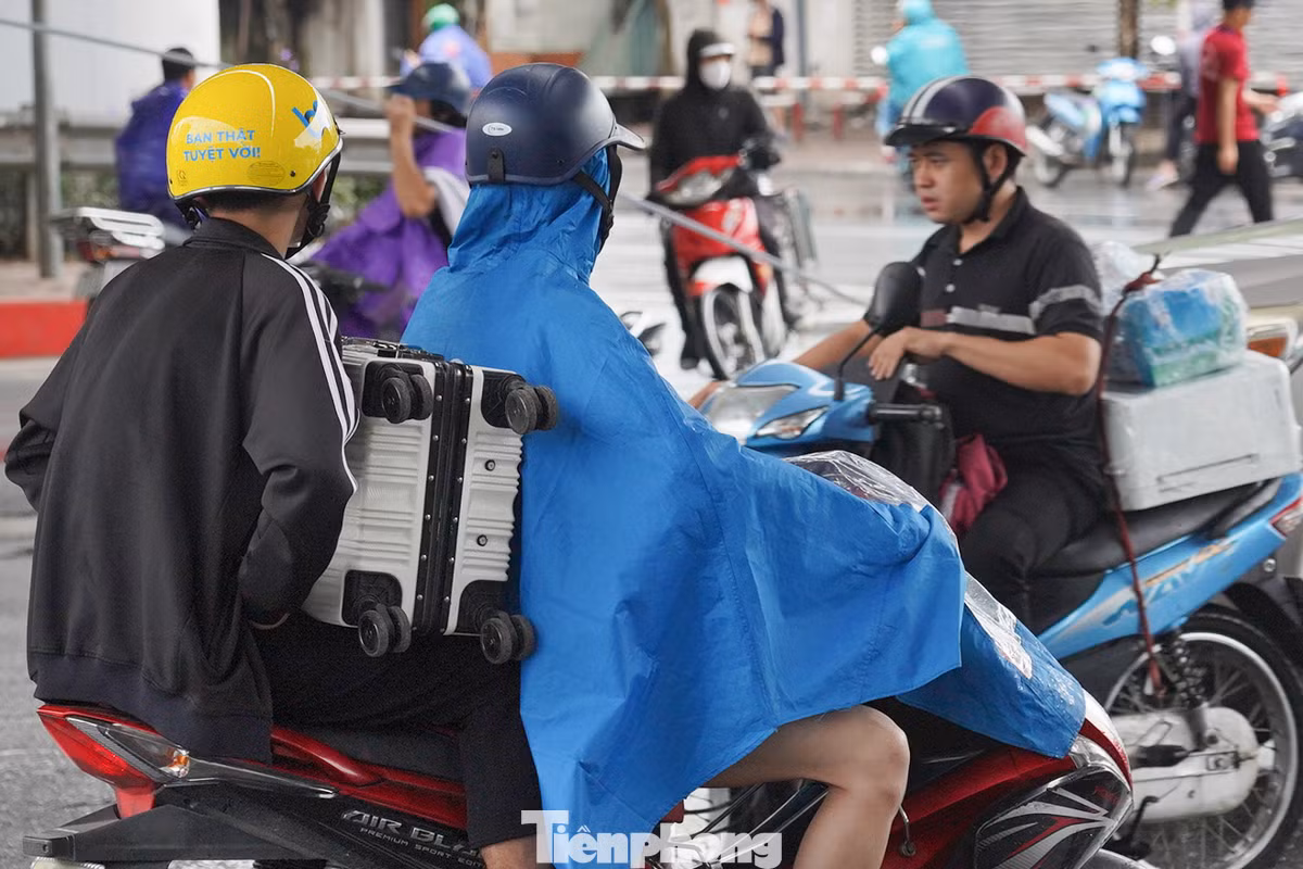 Trời mưa khiến việc ra bến xe trở nên khó khăn trong lớp áo mưa.