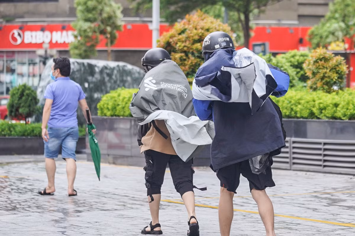 Hai bạn trẻ chới với trong gió, áo mưa bay phần phật.