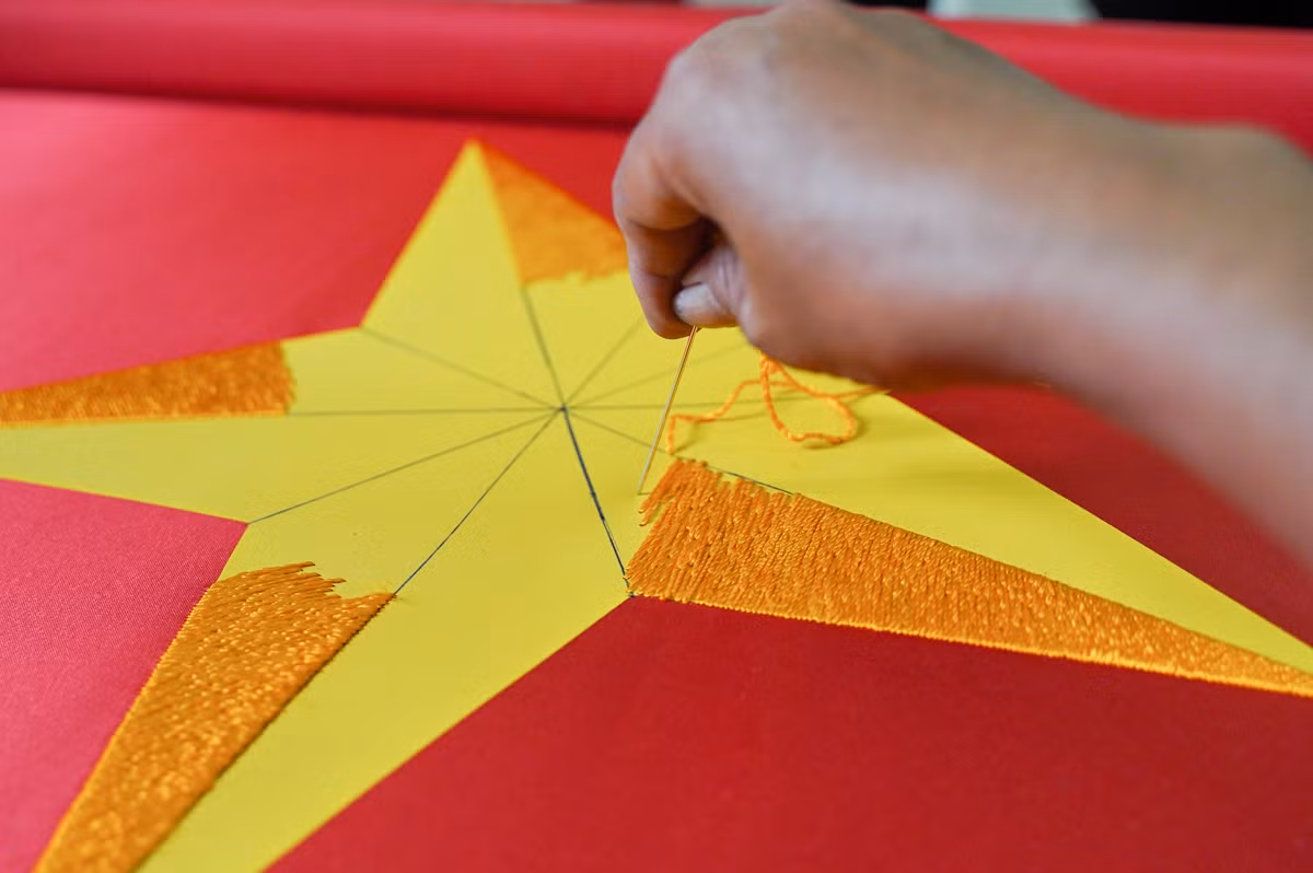 Từng đường kim mũi chỉ đều đặn, chính xác, tạo nên hình ảnh ngôi sao vàng năm cánh rực rỡ trên nền vải đỏ thắm.