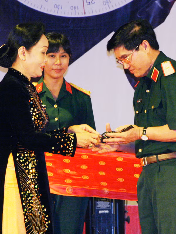 Thiếu tướng Lê Mã Lương tiếp nhận khẩu súng ngắn của cố Trung tướng Nguyễn Văn Tấn - Nguyên tư lệnh quân khu 9, do phu nhân của Trung tướng trao tặng. Ảnh: Ngọc Đinh