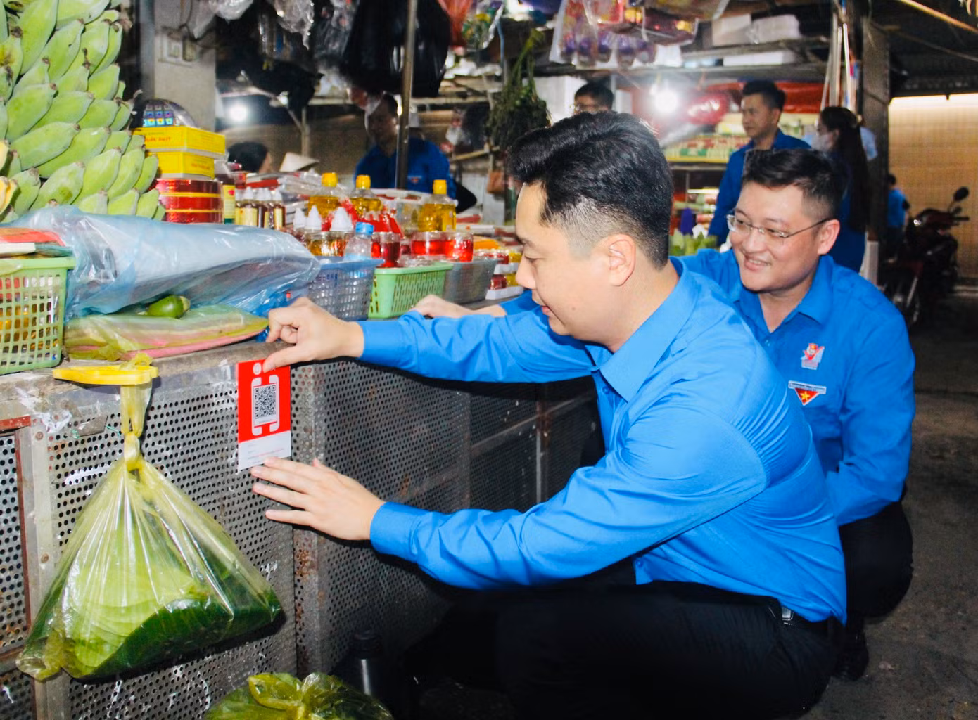 Anh Lê Văn Lương, Bí thư Tỉnh Đoàn Nghệ An dán mã QR tại chợ hưởng ứng ngày cao điểm.