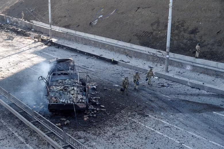 Các binh sĩ Ukraine đi qua một phương tiện bị phá huỷ ở Kiev ngày 26/2. Ảnh: Reuters Các binh sĩ Ukraine đi qua một phương tiện bị phá huỷ ở Kiev ngày 26/2. Ảnh: Reuters