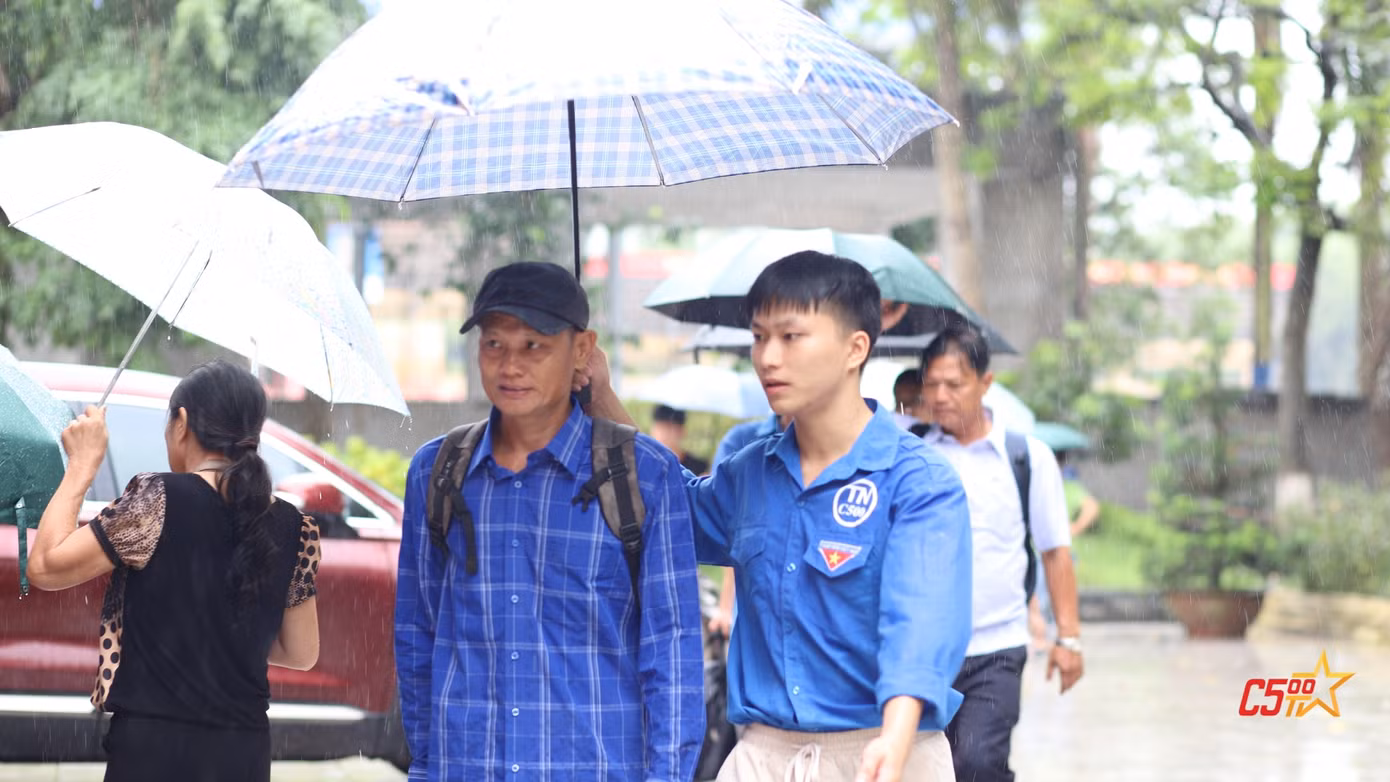 Đội tình nguyện hỗ trợ hướng dẫn tân sinh viên và phụ huynh đến địa điểm buổi lễ khi thời tiết không thuận lợi.