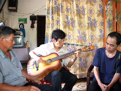Ông Tiến chơi đàn cùng người dân trong xóm. Ảnh: nguyễn huy