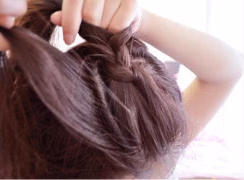 Rẽ phần lệch sang một bên Tết từ trước ra sau, đến đỉnh đầu thì tết ngang sang một bên và cố định lại Ở bên đối diện bạn cũng tết một lọn tóc từ trên đỉnh đầu xuống. Phần đuôi tóc bạn dùng máy uốn xoăn lên để tạo độ phồng cho tóc.