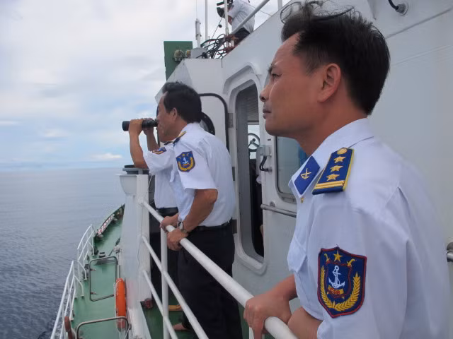 Các chiến sĩ cảnh sát biển sử dụng ống nhòm quan sát những chiếc tàu cá lạ từ xa.