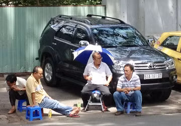 Người đàn ông tên Điểu (che dù) đang điều hành việc “thu phí” trên đường Lê Văn Hưu