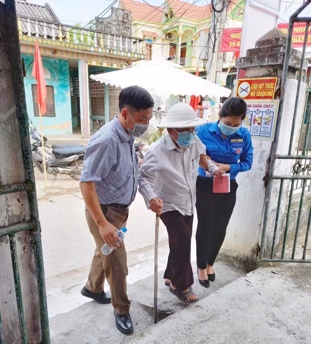 Bóng áo xanh của thanh niên tình nguyện hỗ trợ người dân tham gia bầu cử.