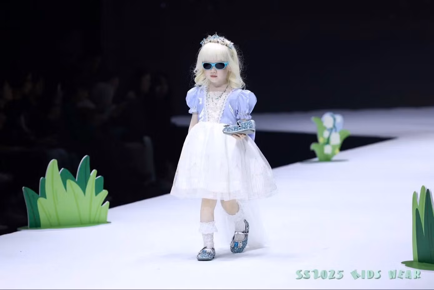 Với mái tóc trắng tự nhiên và phong thái tự tin, cô bé bước ra như công chúa Lọ Lem cầm trên tay chiếc hài nhỏ. - Ảnh: Douyin nhân vật