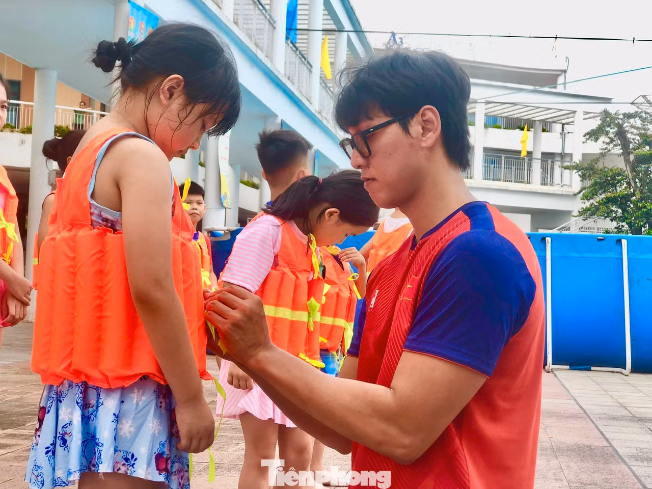 Kình ngư Hoàng Quý Phước hướng dẫn các em mặc áo bơi, khởi động trước khi xuống bể bơi
