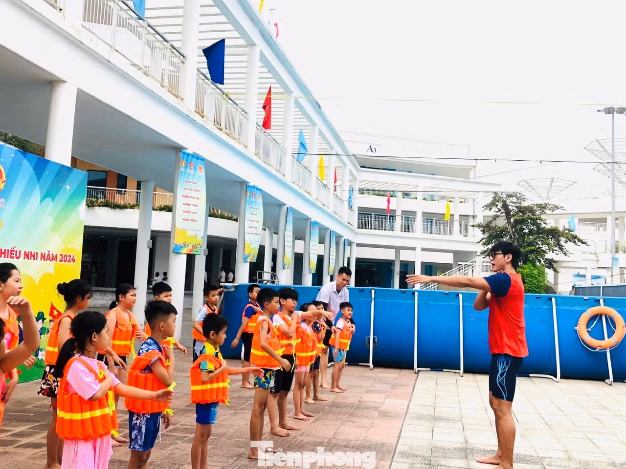 Kình ngư Hoàng Quý Phước hướng dẫn các em mặc áo bơi, khởi động trước khi xuống bể bơi